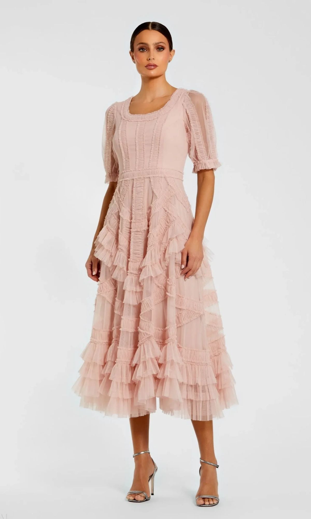 A woman wears the Mac Duggal 8248 Midi Wedding Guest Dress in light pink, featuring ruffles, a midi skirt, and short puff sleeves, paired with silver high-heeled sandals against a plain white background.